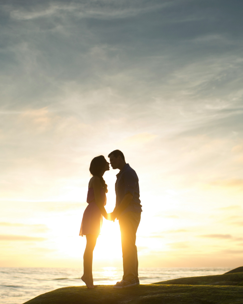 Couple qui s'embrasse à contrejour devant l'océan