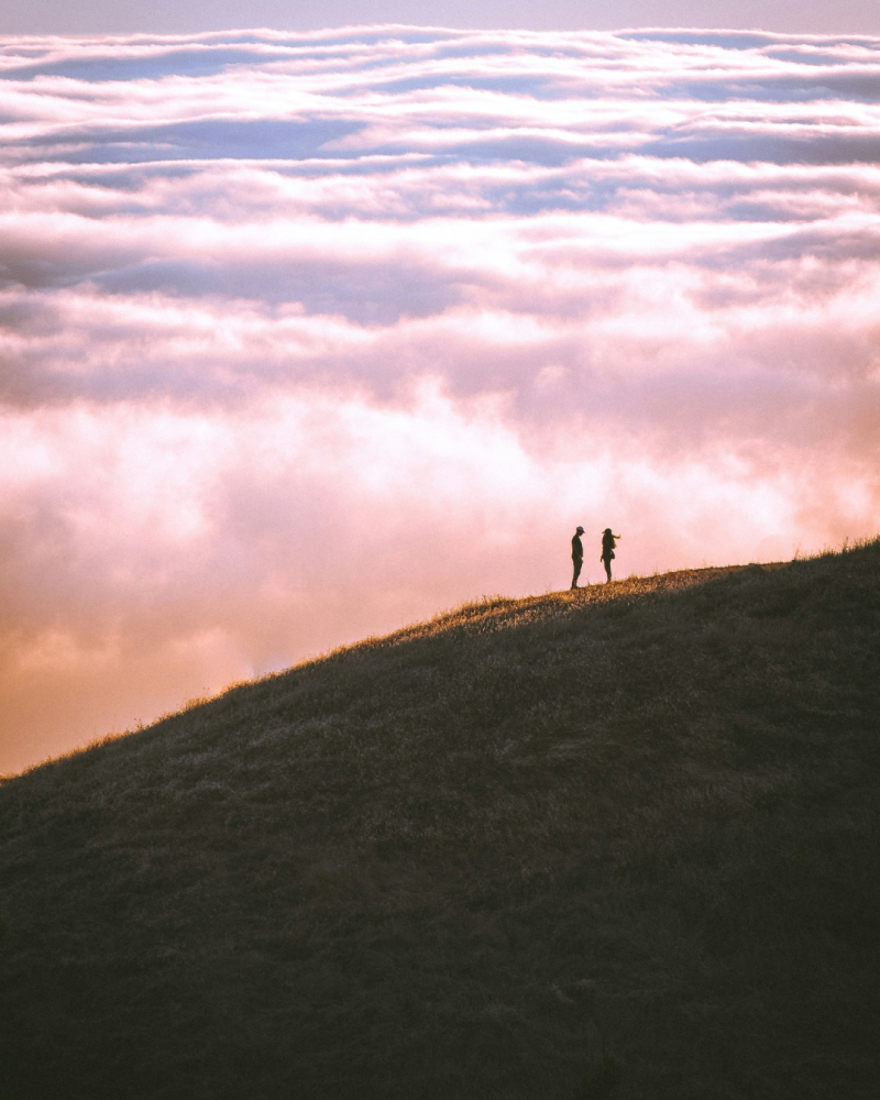Couple sur une colline avec des nuages en contrebas