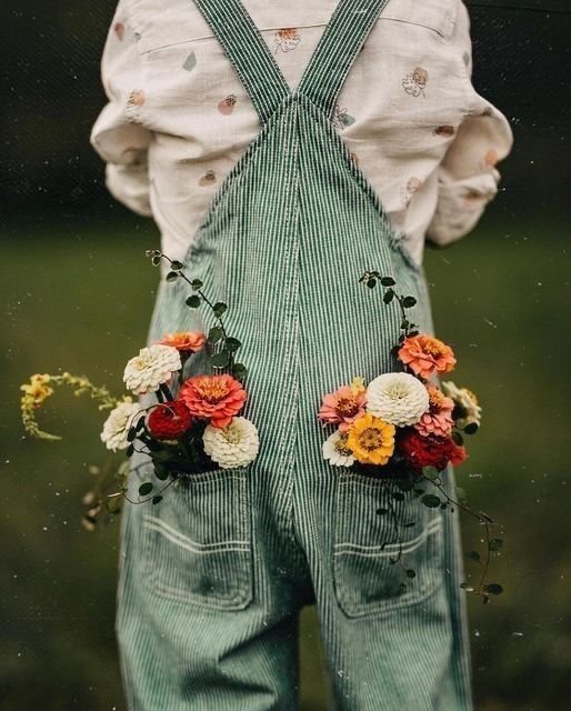Enfant en salopette rayée tenant des fleurs colorées glissées dans ses poches