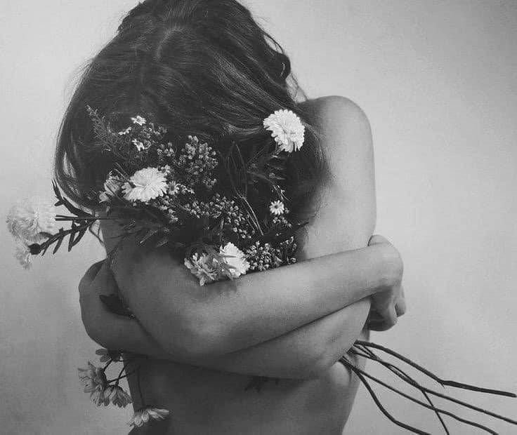 femme torse nue serrant un bouquet de fleurs en noir et blanc
