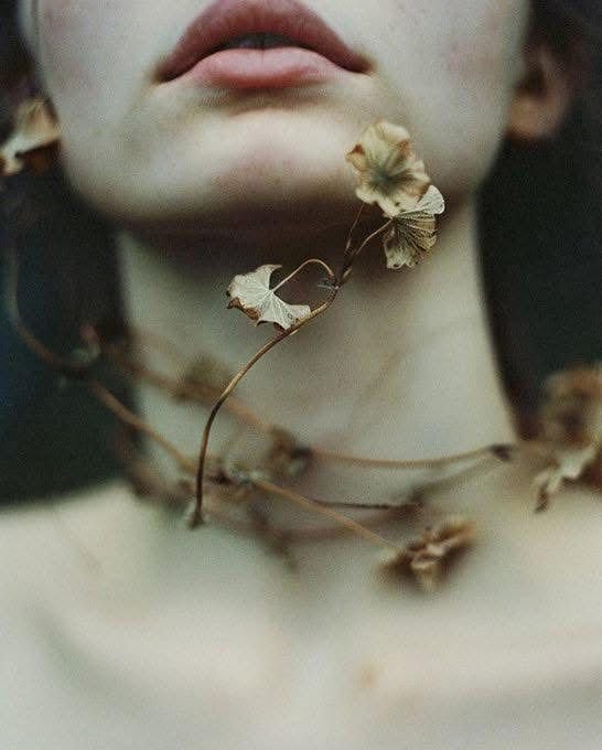 bas de visage d'une femme avec des branchages autour du cou