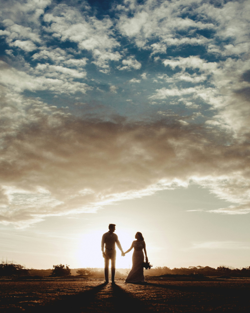 Couple de mariés se tenant par la main à contre jour