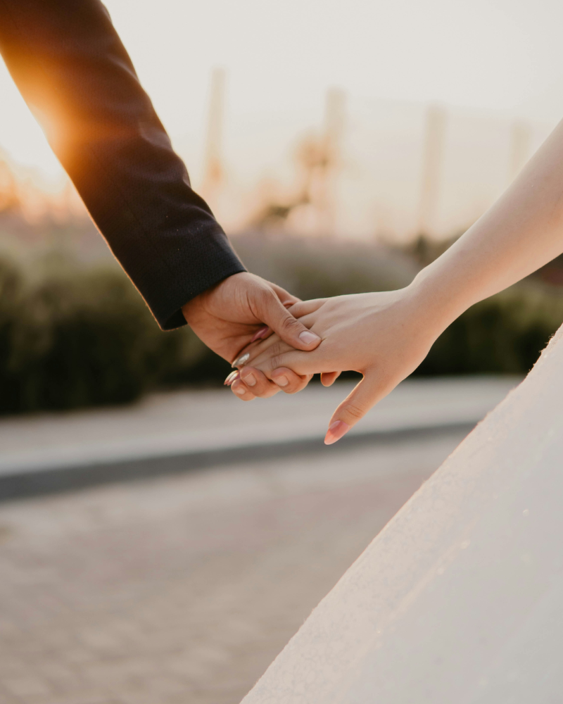 Couple de mariés se tenant par la main à contre jour