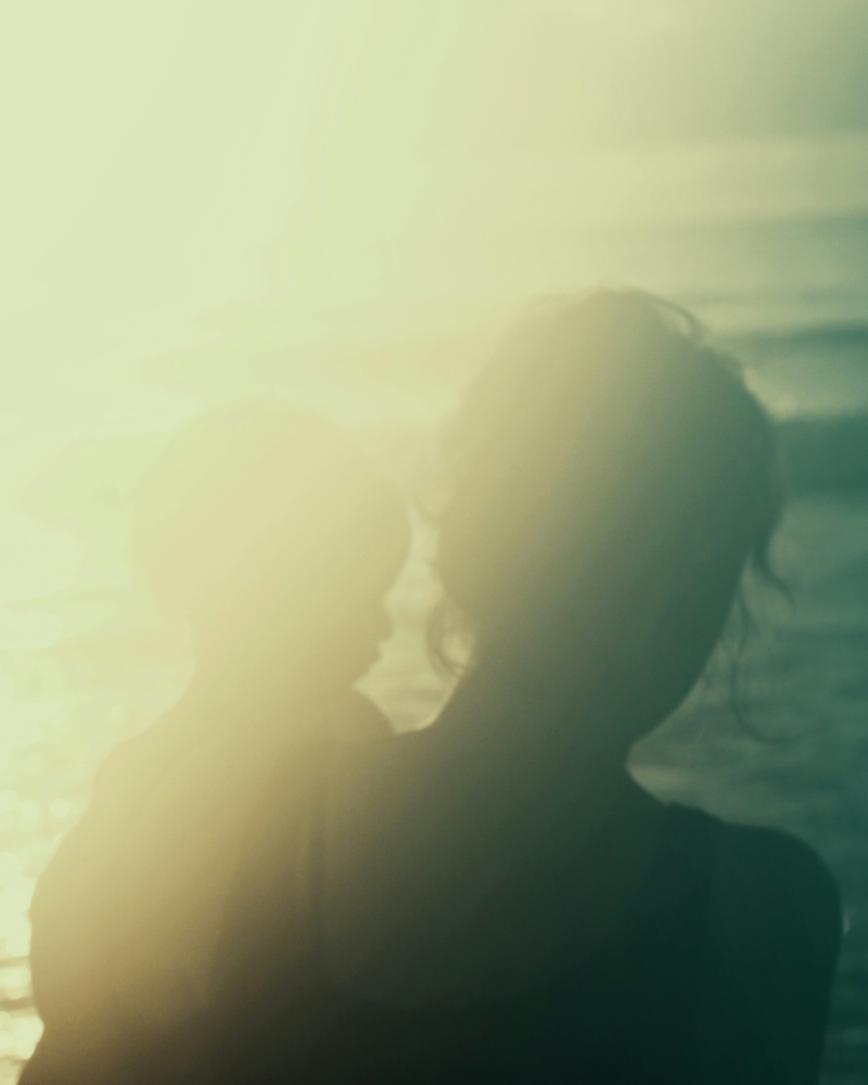 Photo à contre-jour d'une mère portant son enfant dans les bras sur une plage